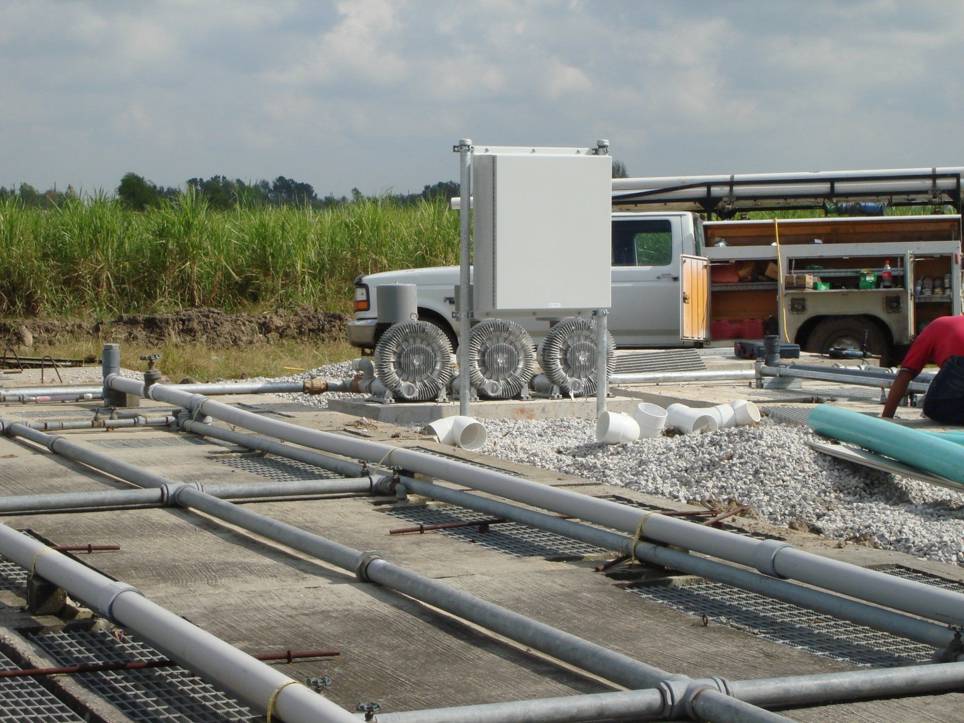 A man in a red shirt is working on pipes in a field