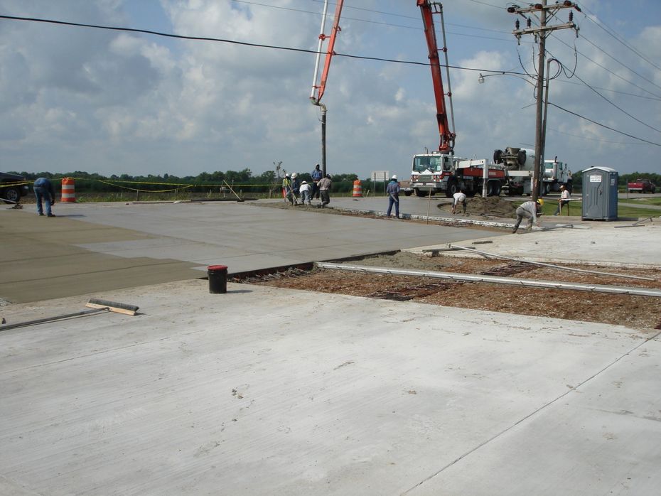 A concrete pump is being used to pour concrete into a parking lot