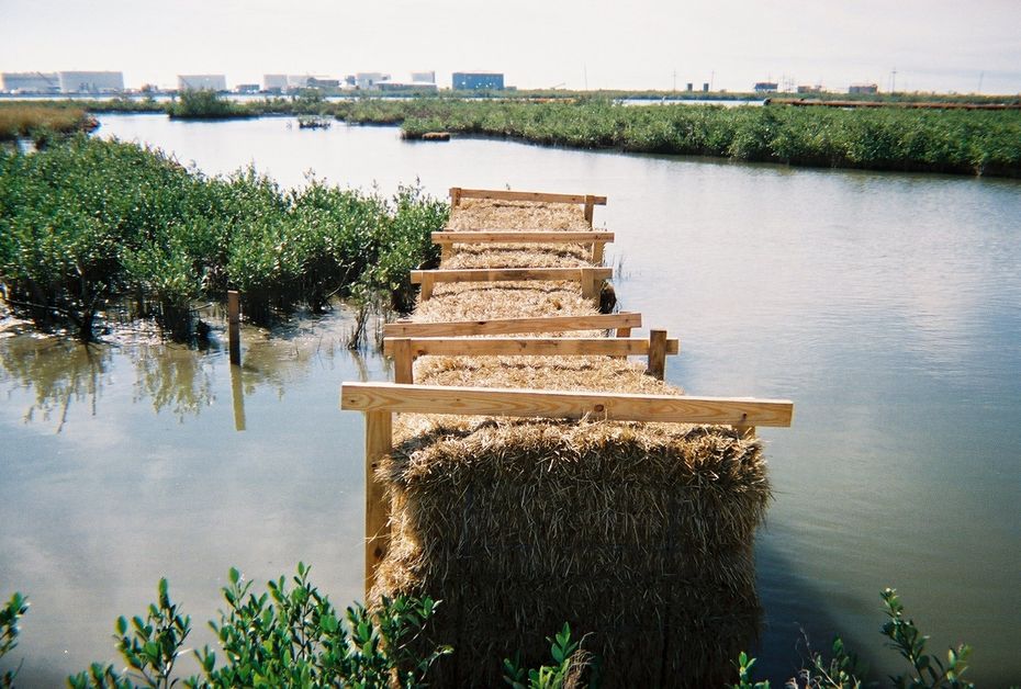 A bridge made of hay bales over a body of water