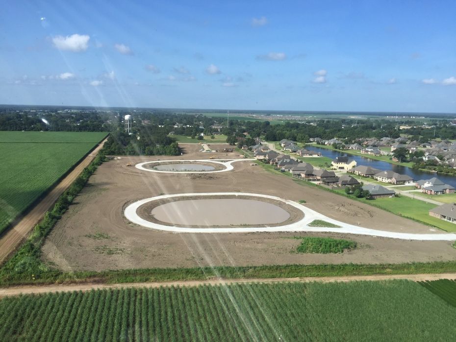 An aerial view of a residential area surrounded by fields and houses.