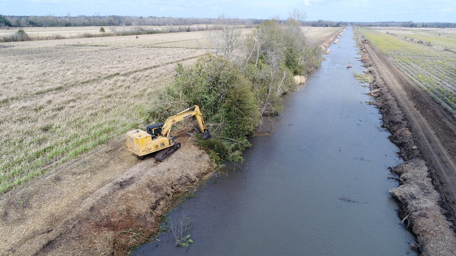 An aerial view of a yellow excavator working on a river.
