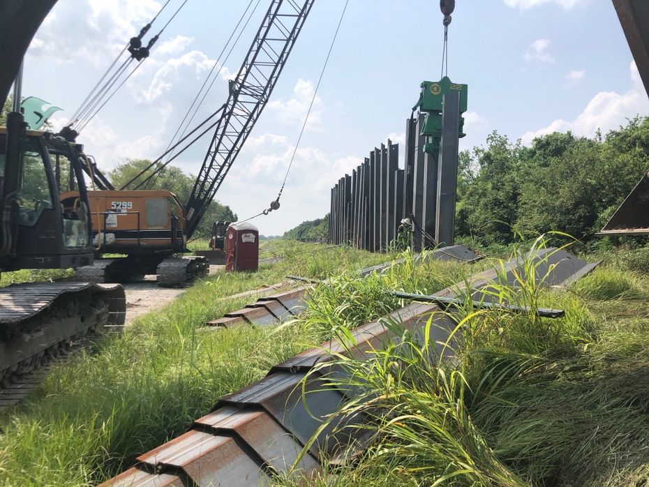 A crane is lifting a pile of concrete in a field.