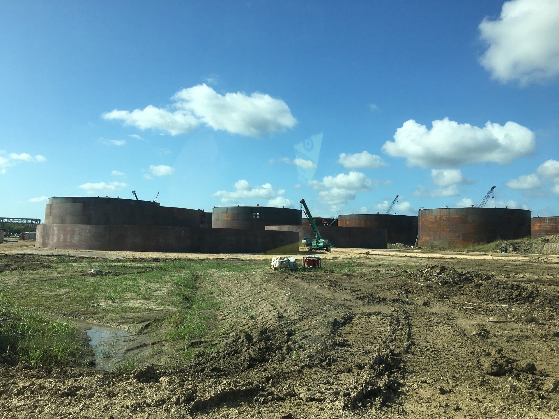 A row of large tanks in a field with a blue sky in the background