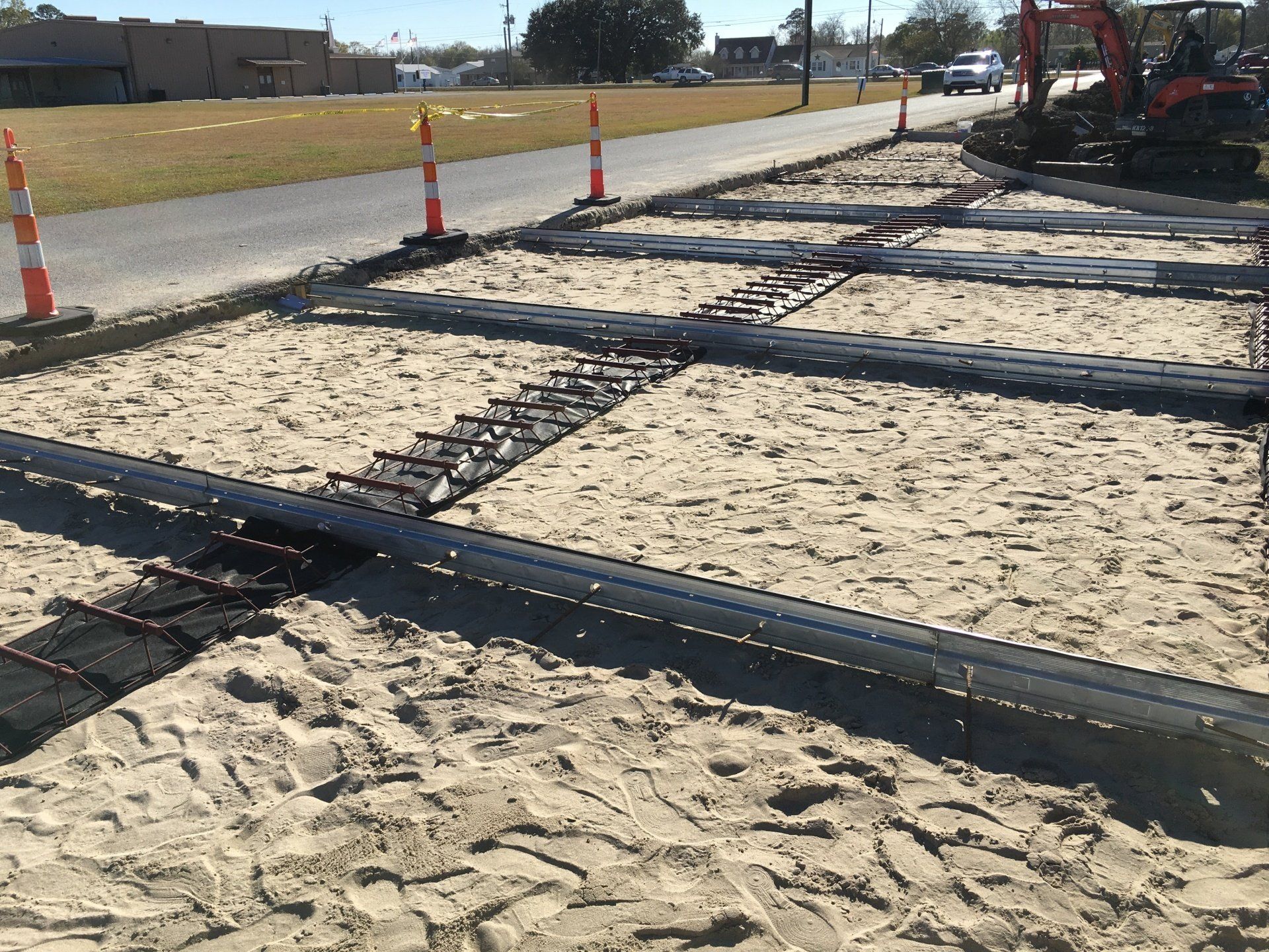 A construction site with a lot of sand and a tractor in the background.