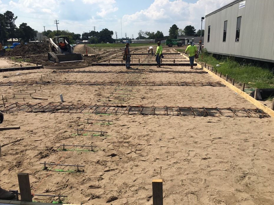 A group of construction workers are walking through a dirt field.