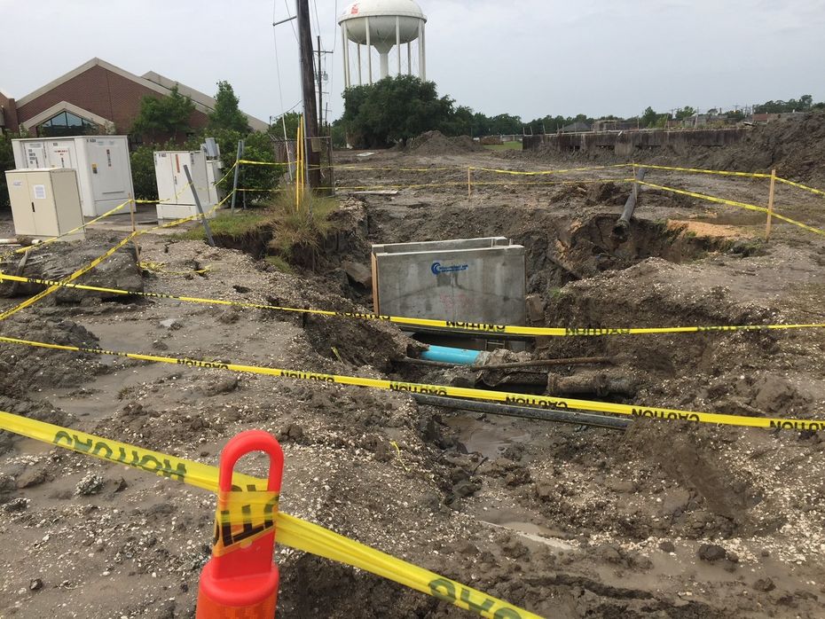 A muddy construction site with a water tower in the background.