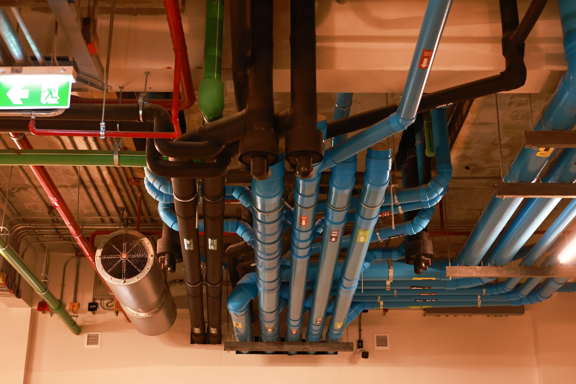 Ceiling with blue and black industrial pipes and ducts in a mechanical room