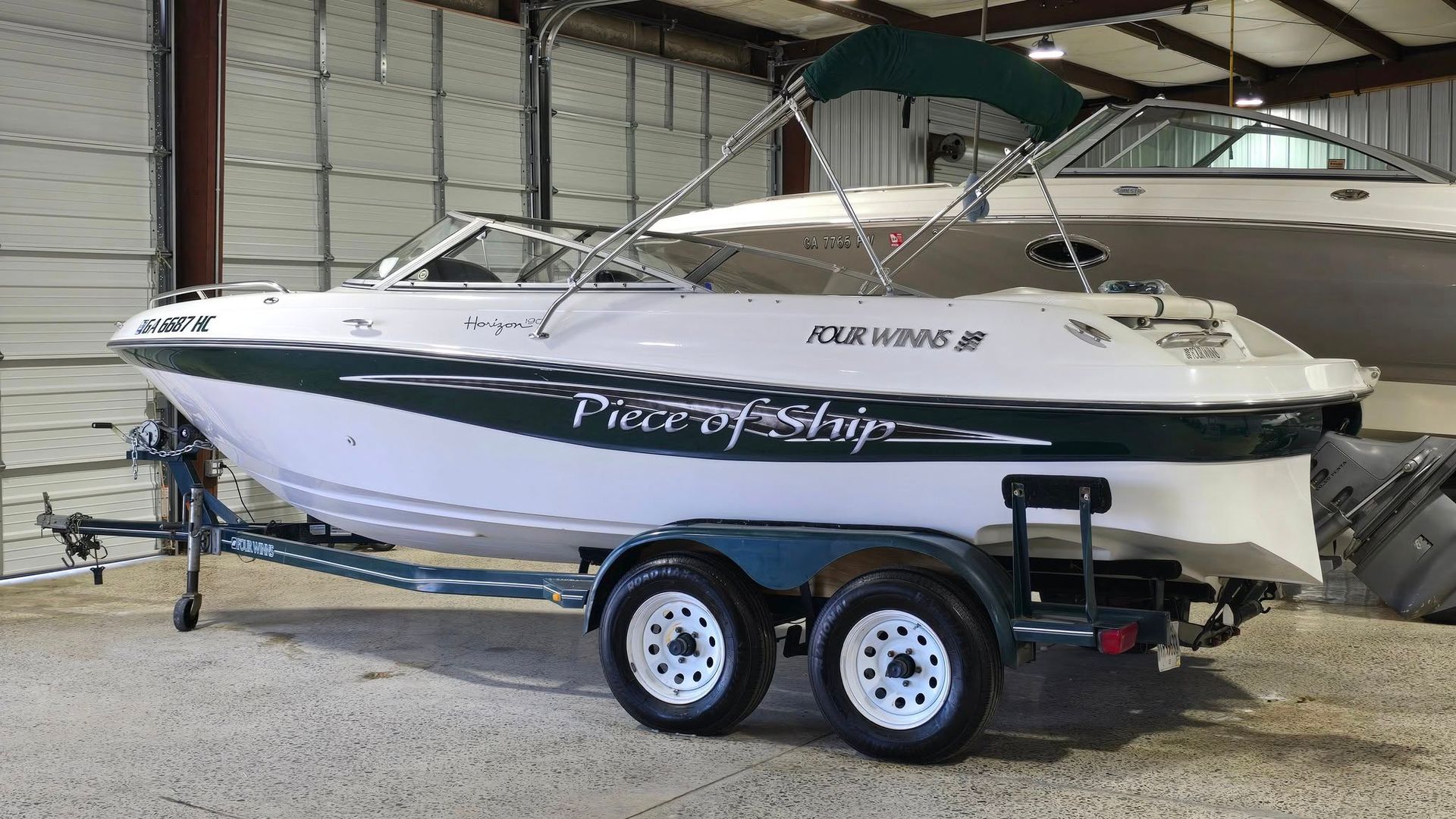 White and green pleasure boat on a trailer, inside a building. 