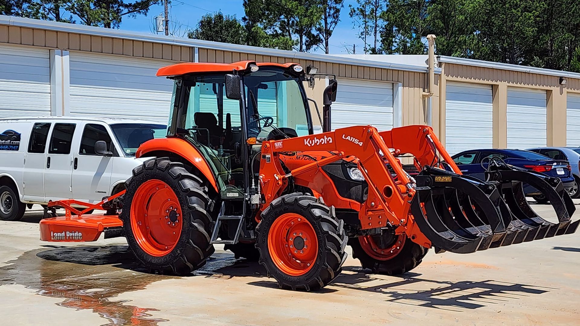 Orange Kubota tractor with a front loader and grapple attachment.