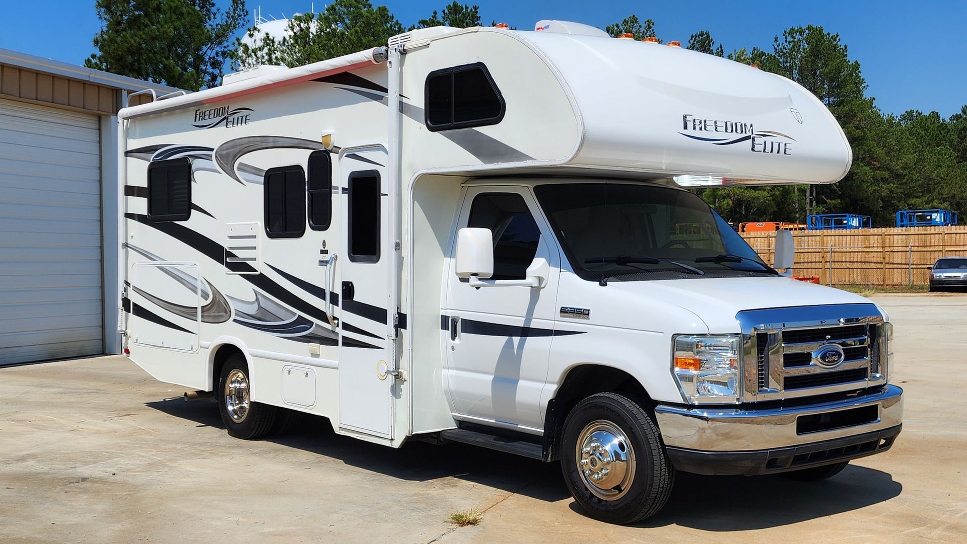 White RV parked outside a building, sunny day.
