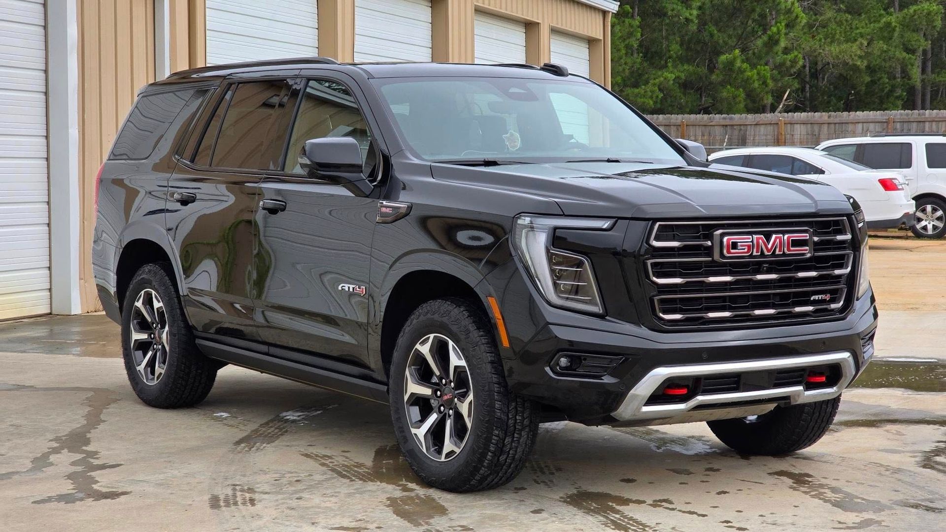 Black GMC Yukon SUV parked in front of a building with open garage doors.
