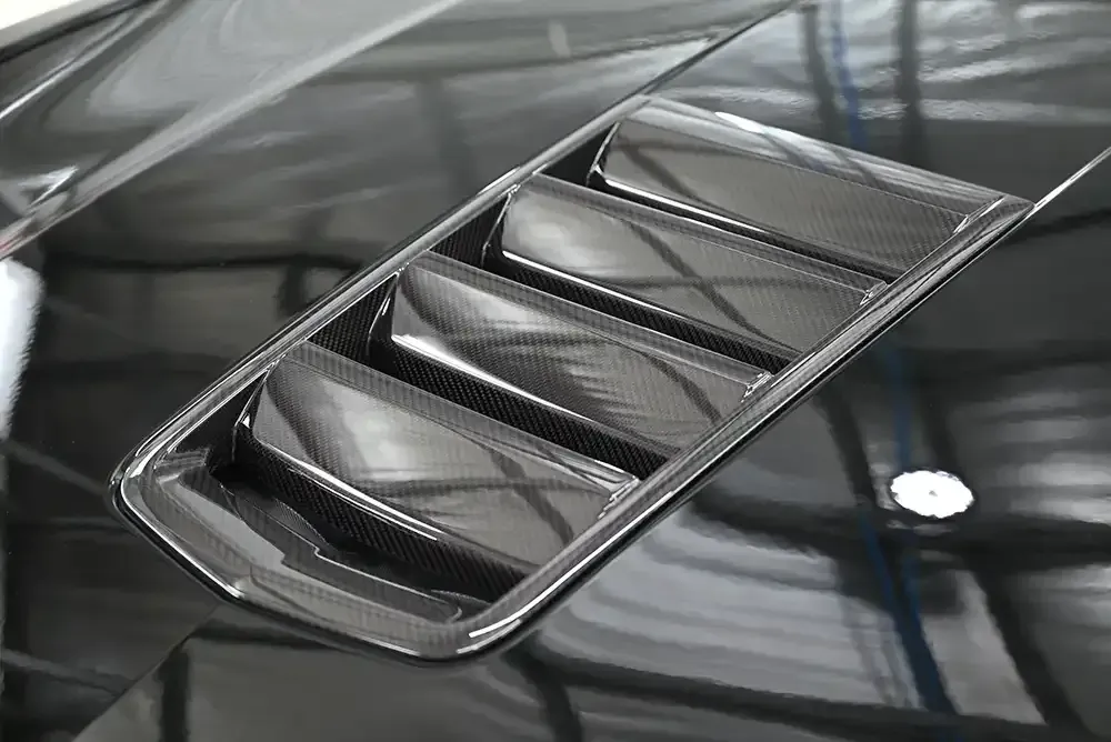 Carbon fiber hood vent on a black car hood.