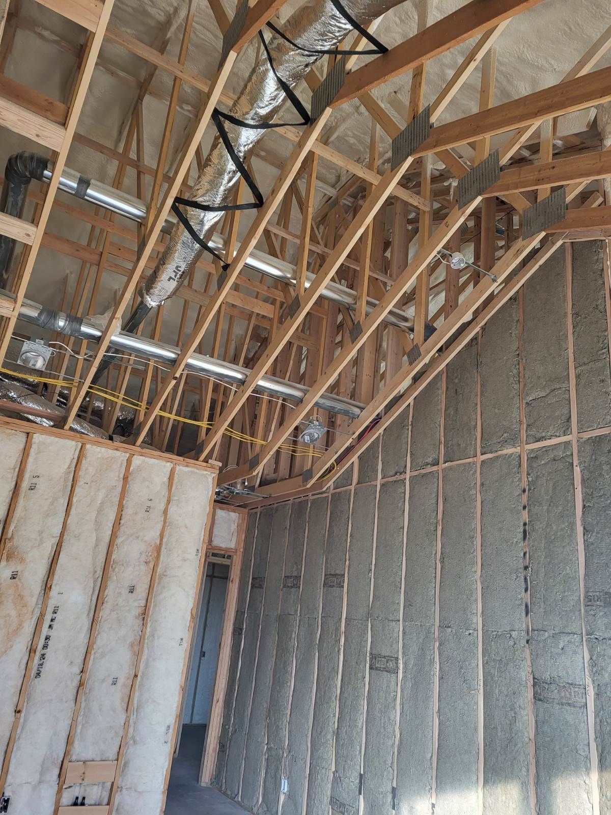 The inside of a building under construction with wooden beams and insulation.