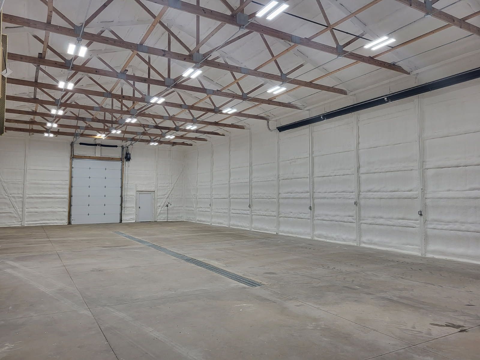 A large empty warehouse with white walls and a white door.