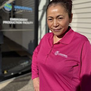 A woman in a pink polo shirt is standing in front of a building.