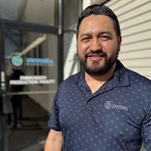 A man with a beard is standing in front of a building.