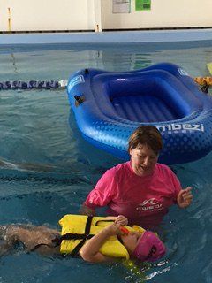Young boy learning to swim in supervision of a woman trainer