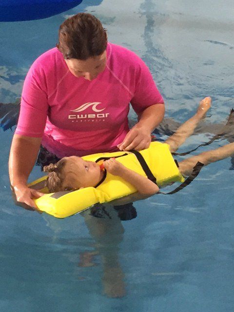 Young boy learning to swim in supervision of a woman trainer