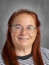 A woman wearing glasses and a striped shirt is smiling for the camera.