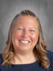 A woman in a blue shirt is smiling for the camera.