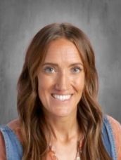 A woman with long brown hair is smiling for the camera.