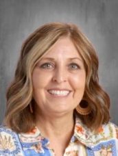 A woman with brown hair and earrings is smiling for the camera.
