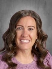 A woman in a purple shirt is smiling for the camera.