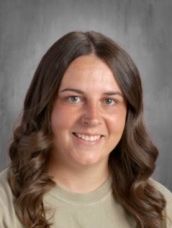 A young woman with long brown hair is smiling for a picture.
