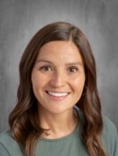 A woman in a green shirt is smiling for the camera.