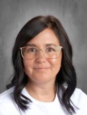 A woman wearing glasses and a white shirt is smiling for the camera.