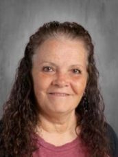 A woman with long curly hair is smiling for the camera.