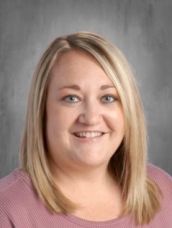 A woman in a pink shirt is smiling for the camera.