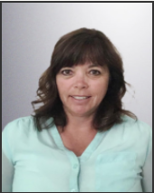 A woman in a light blue shirt is smiling for the camera