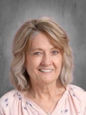 A woman in a pink shirt is smiling for the camera.