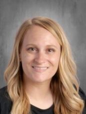 A woman with blonde hair and a black shirt is smiling for a picture.