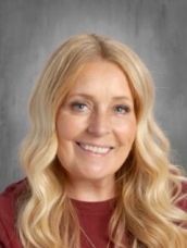 A woman with blonde hair is wearing a red shirt and smiling for the camera.