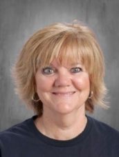 A woman in a blue shirt is smiling for the camera.