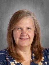 A woman in a blue floral shirt is smiling for the camera.