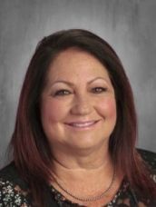 A woman with long hair and a necklace is smiling for the camera.