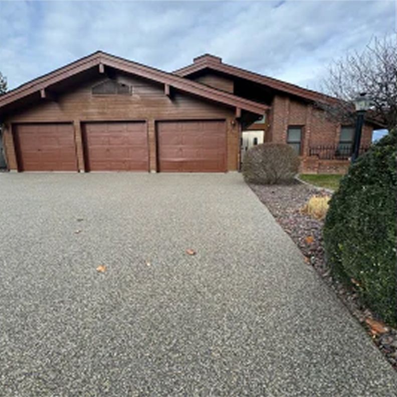A large house with three garage doors and a driveway.