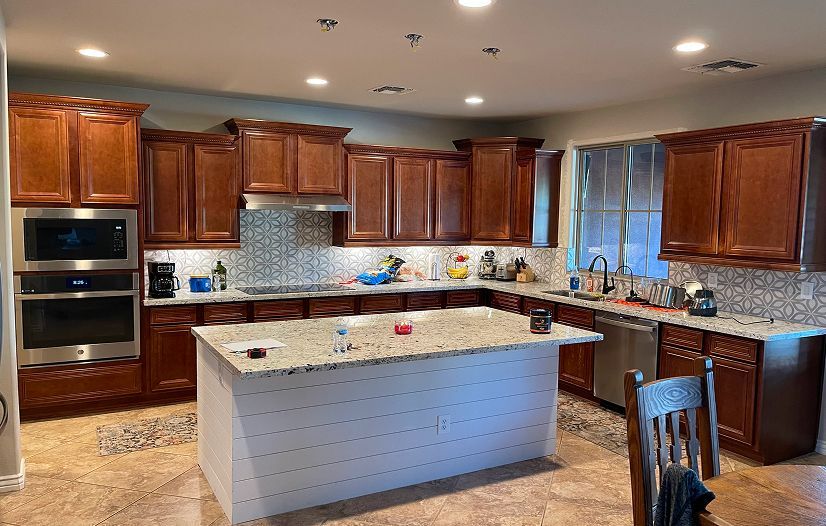 A kitchen with wooden cabinets , granite counter tops , stainless steel appliances and a large island.