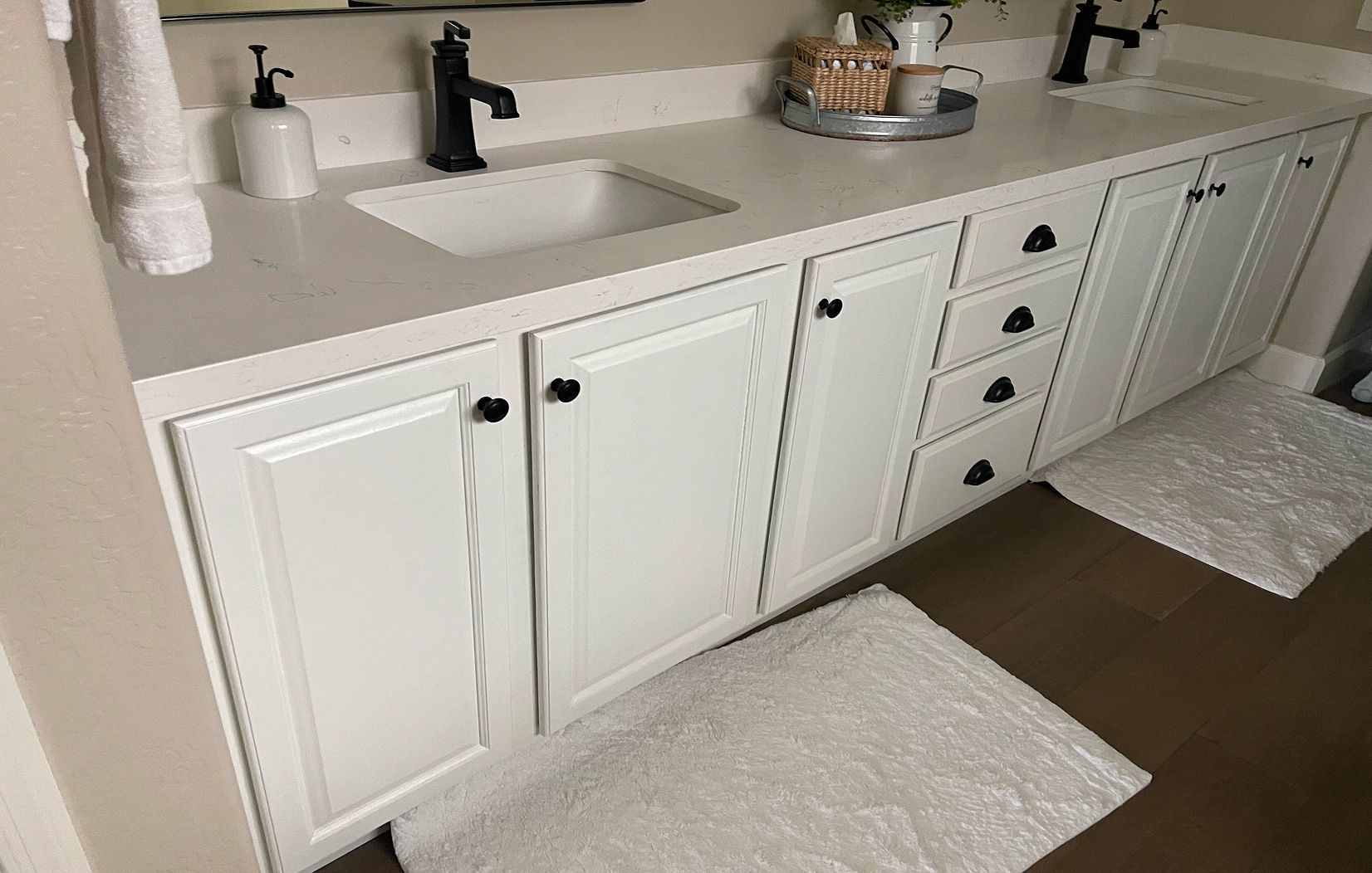 A bathroom with white cabinets , a sink , and a mirror.