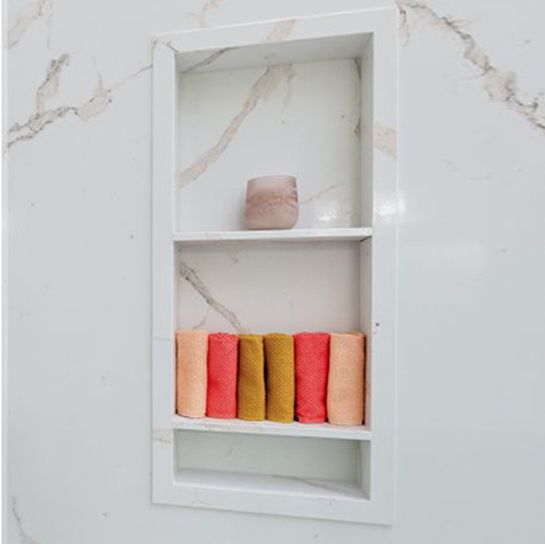 A bathroom shelf with towels and a vase on it.