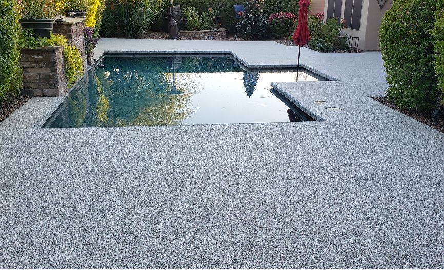 A large swimming pool is surrounded by a concrete patio.