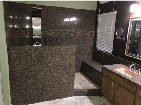 A bathroom with a sink , mirror and walk in shower.