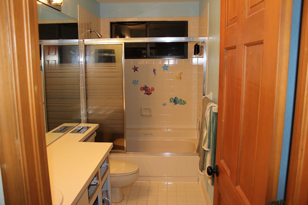 A bathroom with a toilet , shower , sink and mirror.