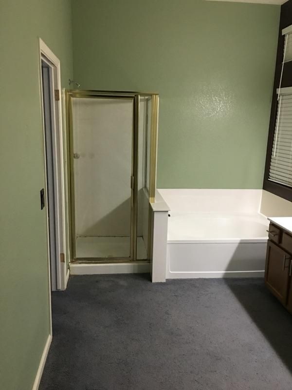 A bathroom with a tub , shower , and window.