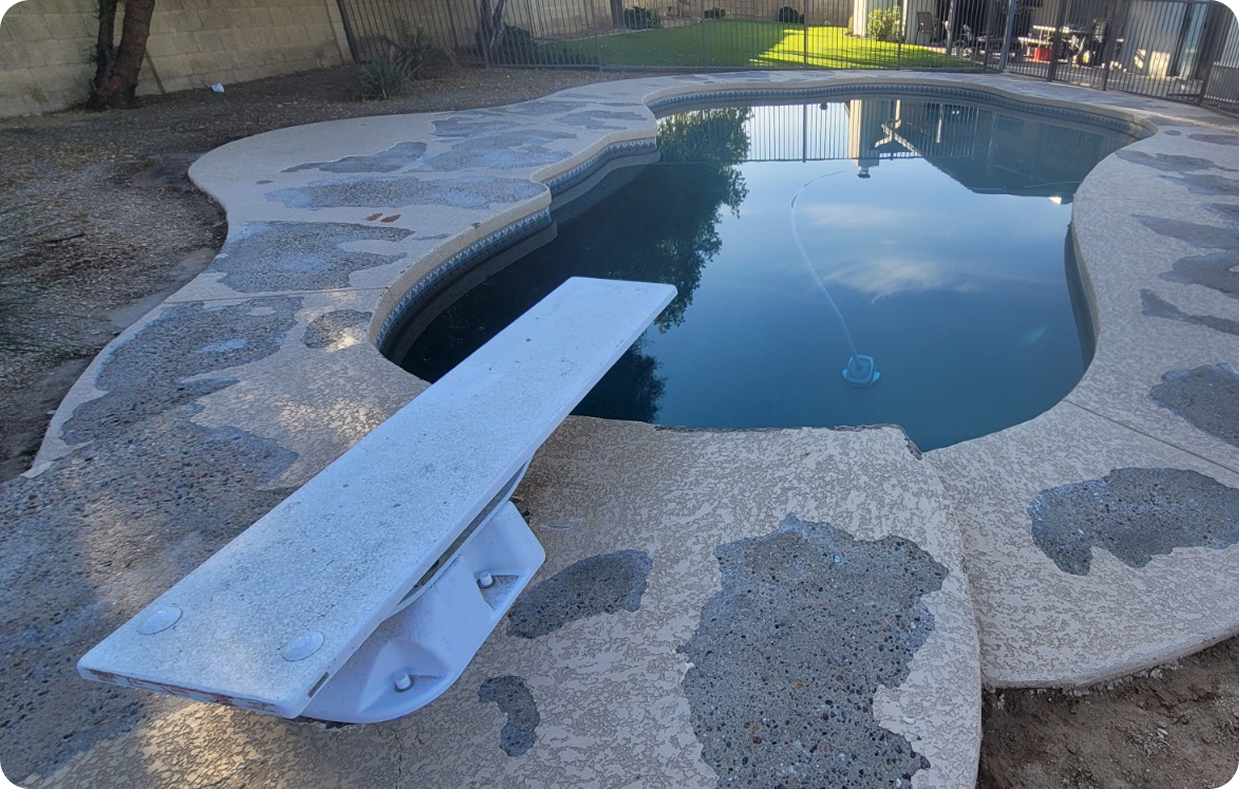 A diving board is sitting next to a swimming pool