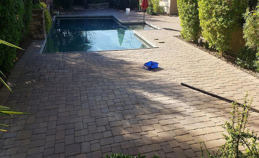 A brick patio with a swimming pool in the background.