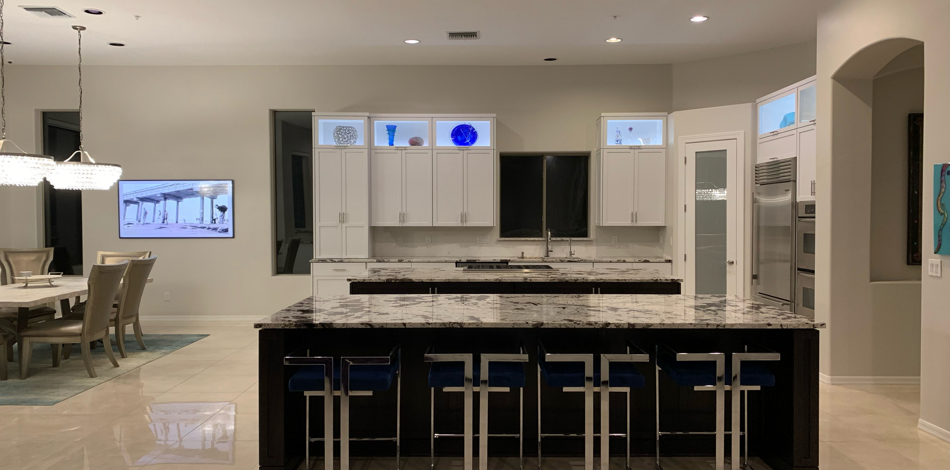 A kitchen with white cabinets , granite counter tops , stainless steel appliances and a large island.